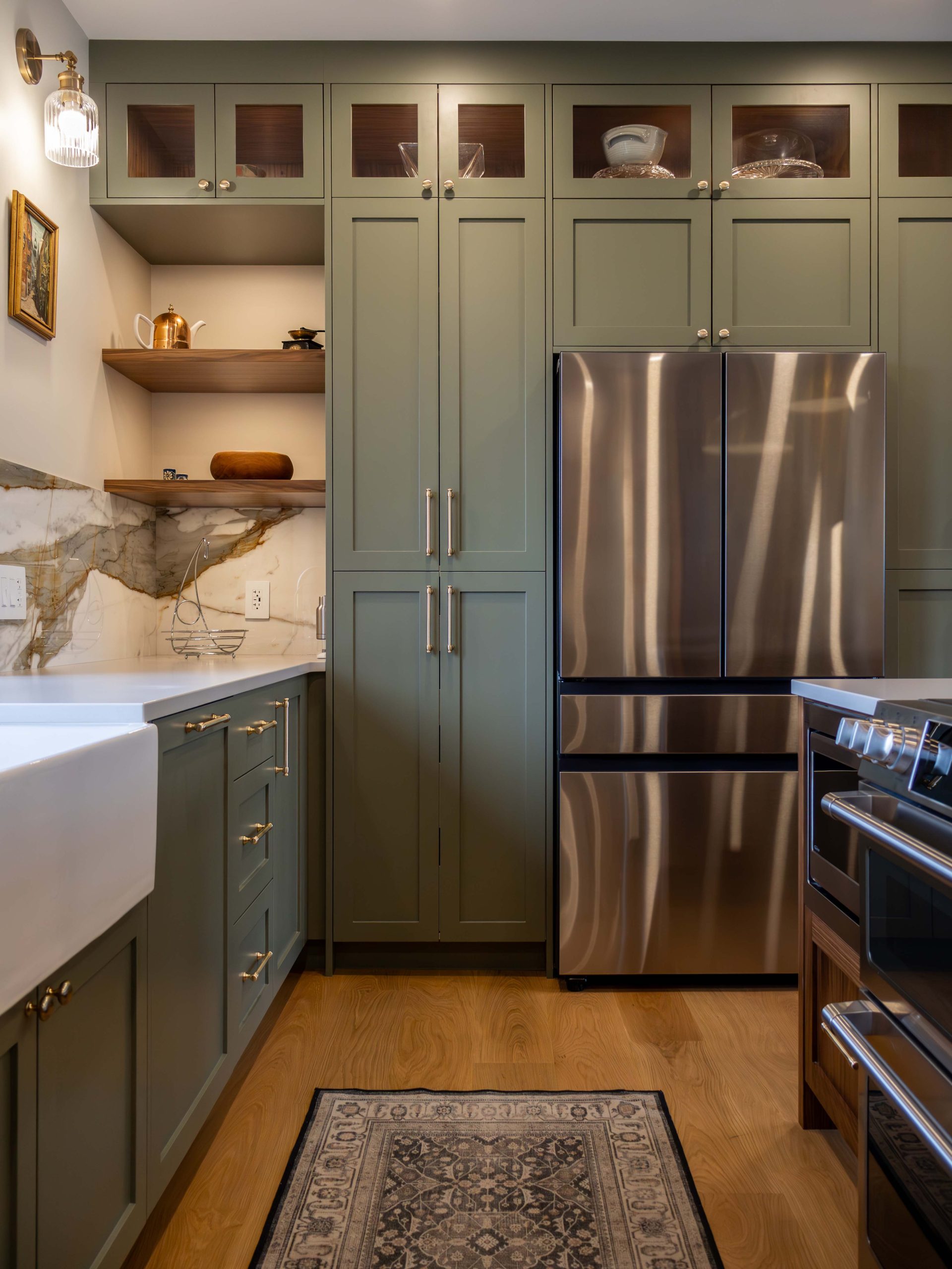 Nature-inspired kitchen with warm walnut woodwork, earthy green cabinetry, and ambient puck lighting.